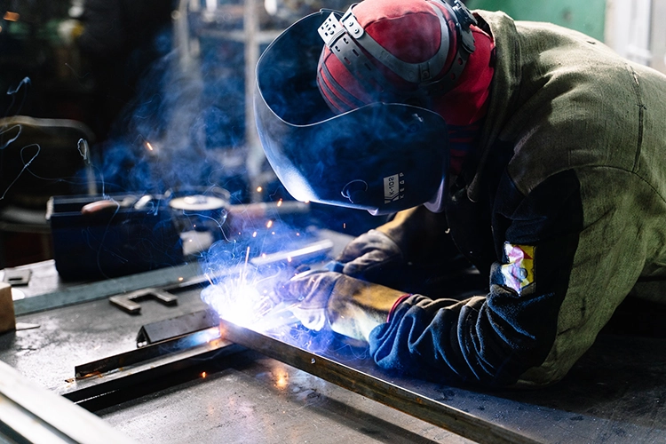 Personne entrain de souder une pièce métallique en inox